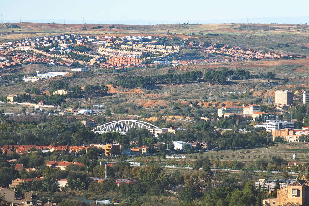 Aerial view showcasing Toledo's urban landscape surrounded by picturesque hills and greenery.